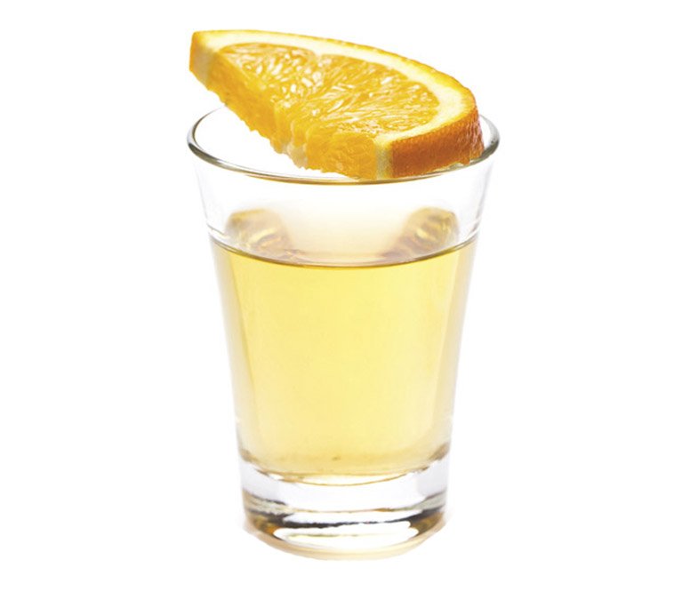 Un trago de mezcal con una rodaja de naranja sobre el trago